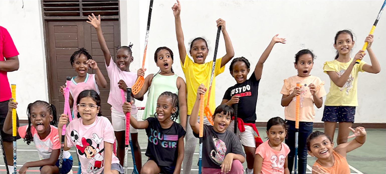 A group of students cheering with their floorball sticks raised
